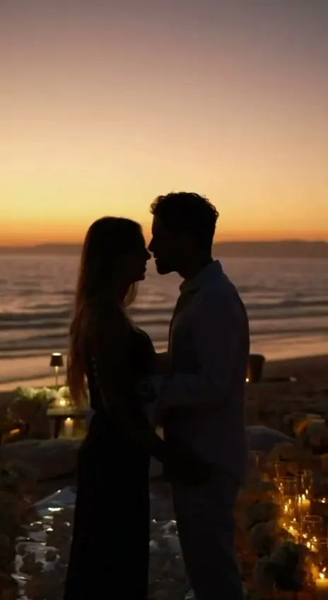 A proposal at sunset: the couple about to kiss among the candles